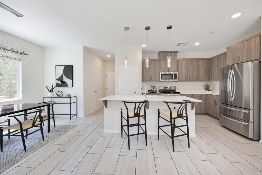 35103 Vine Place Fallbrook, CA 92028 - Photo 22 of 42 a kitchen with stainless steel appliances granite countertop a stove a refrigerator a kitchen island a dining table and chairs with wooden floor