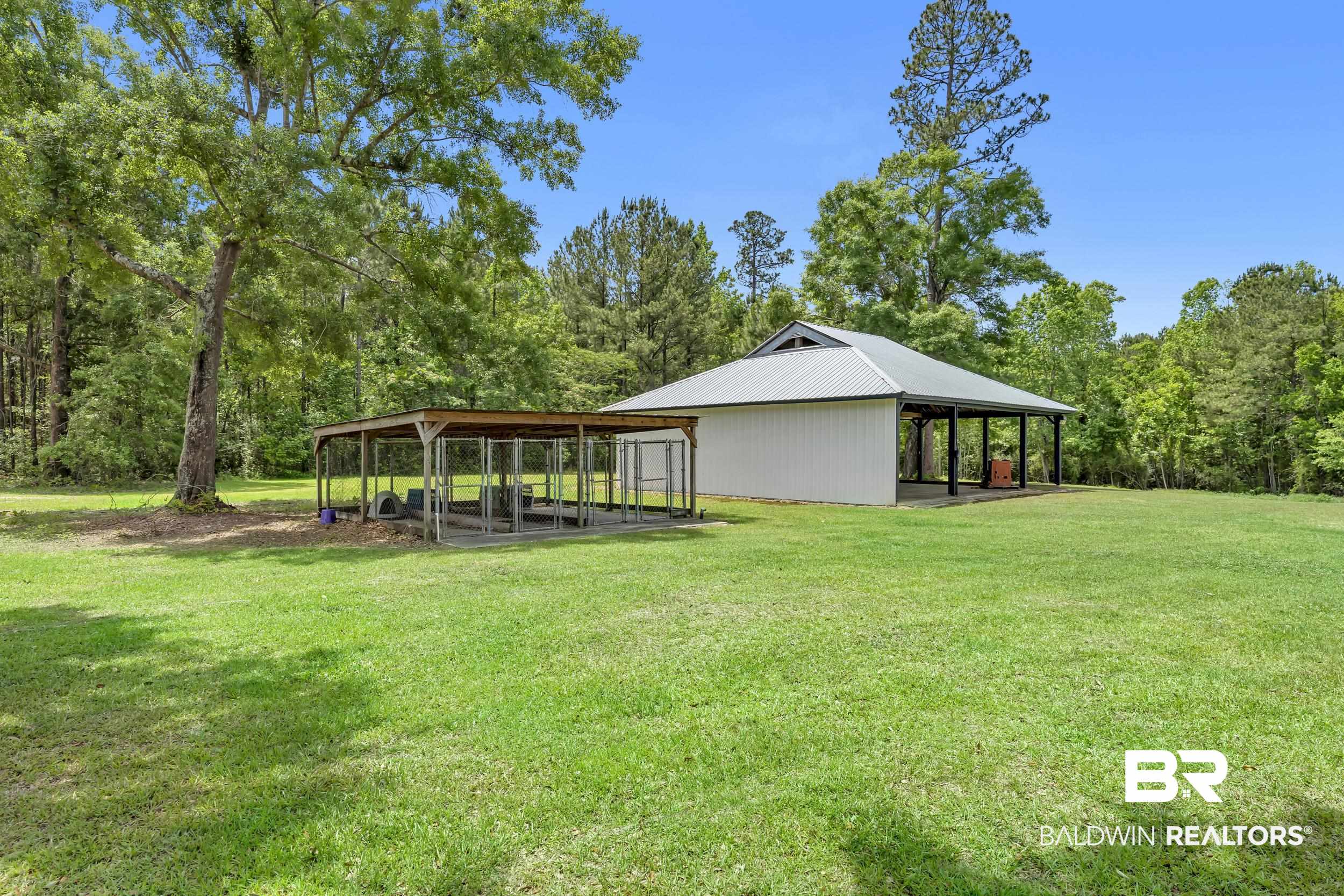 43199 Pine Grove Road Bay Minette, AL 36507 - Photo 14 of 71 Expansive grassy lawn with a white outbuilding featuring a metal roof and an open-air covered porch