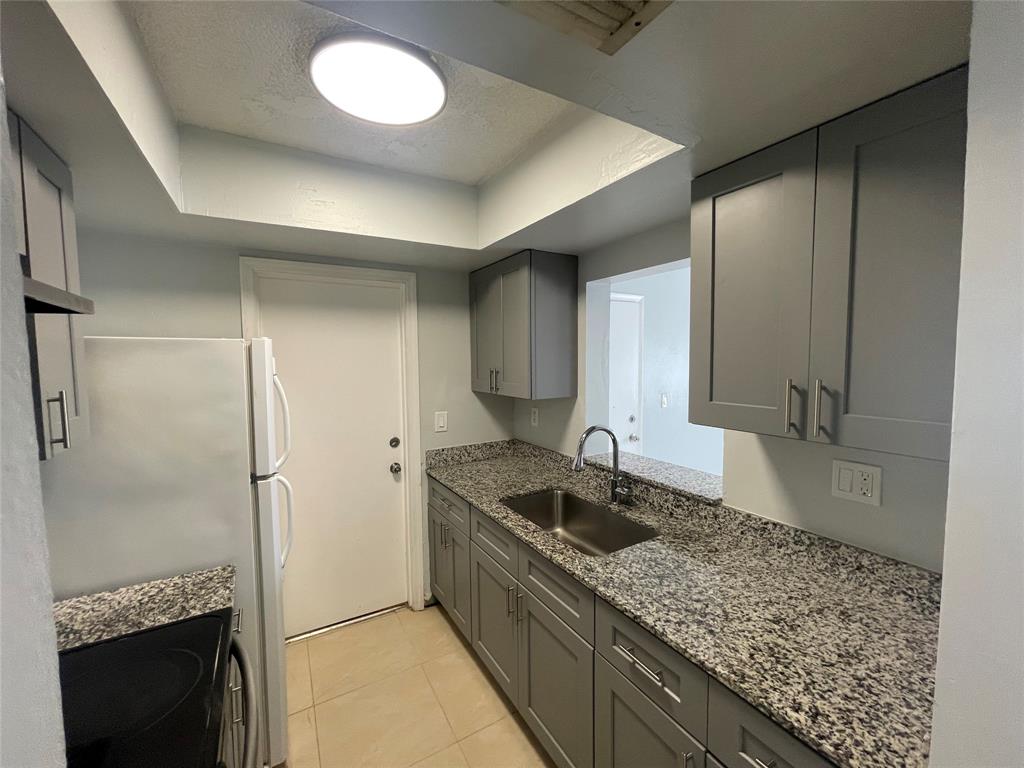 395 Southwest 15th Street, Unit 10 Pompano Beach, FL 33060 - Photo 3 of 14 a kitchen with stainless steel appliances granite countertop a sink stove and refrigerator
