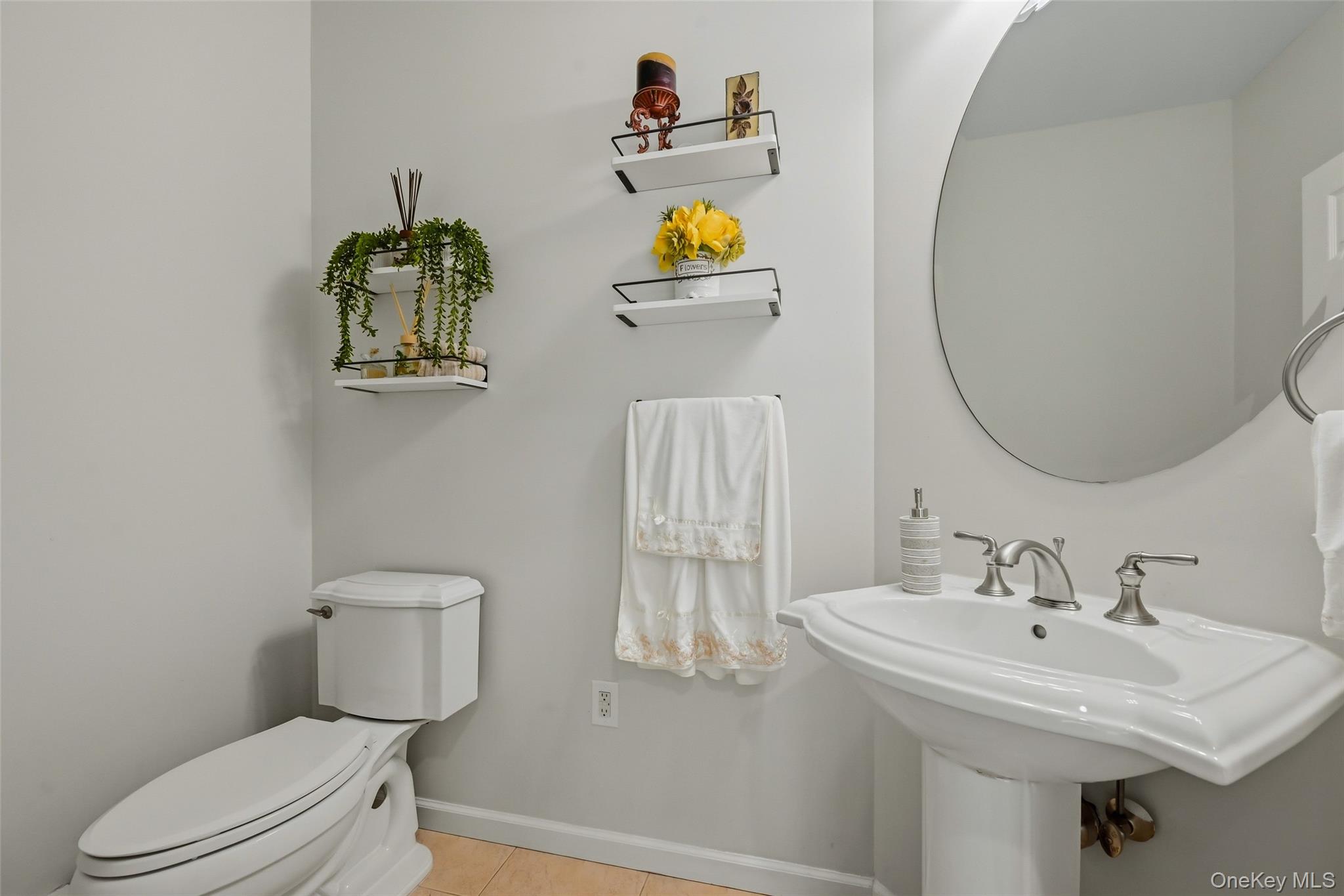 51 Meriwether Trail Congers, NY 10920 - Photo 18 of 50 Pedestal sink with brushed nickel faucet, round wall-mounted mirror, and light wood-finish flooring