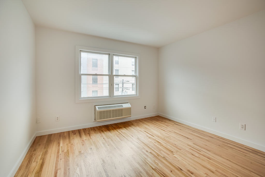 204 Grand Street, Unit 2C Hoboken, NJ 07030 - Photo 11 of 14 an empty room with wooden floor and windows