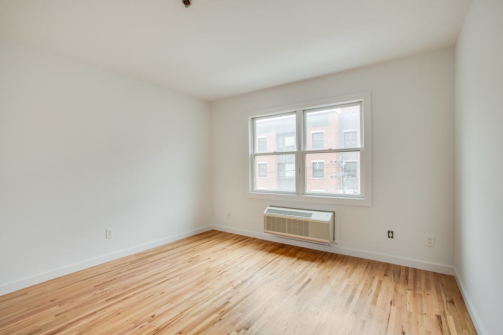204 Grand Street, Unit 2C Hoboken, NJ 07030 - Photo 10 of 14 an empty room with wooden floor and windows