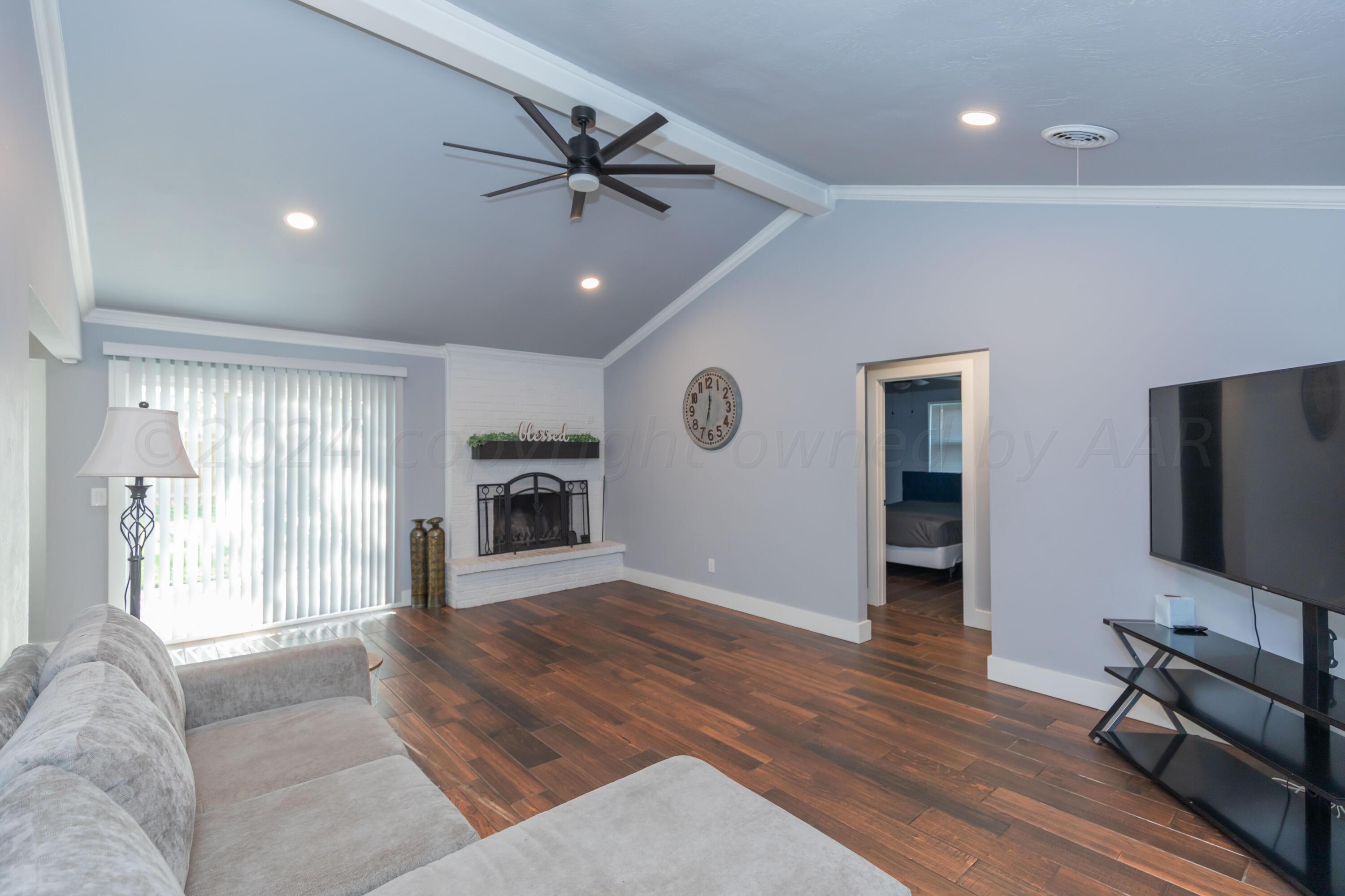 5101 McCarty Boulevard Amarillo, TX 79110 - Photo 3 of 20 a view of a livingroom with a flat screen tv wooden floor and a ceiling fan