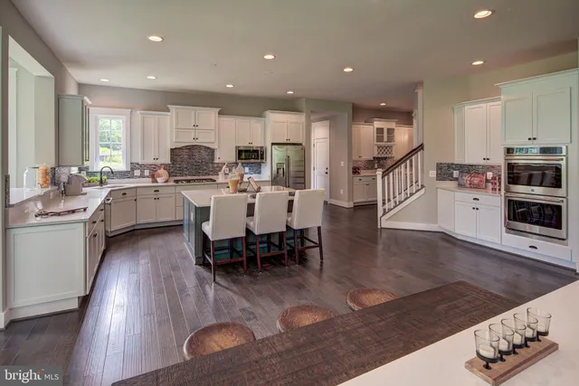 a large dining hall with stainless steel appliances granite countertop a stove a table and chairs with wooden floor