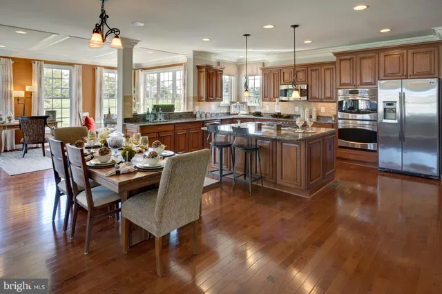 a kitchen with stainless steel appliances granite countertop a stove a refrigerator a kitchen island a dining table and chairs