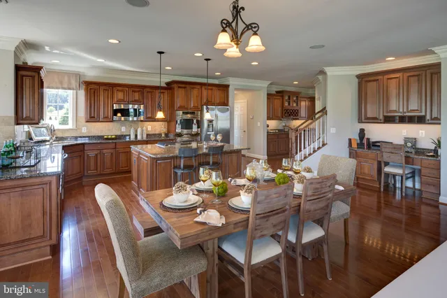 a dining room with kitchen island furniture a chandelier stainless steel appliances and wooden floor