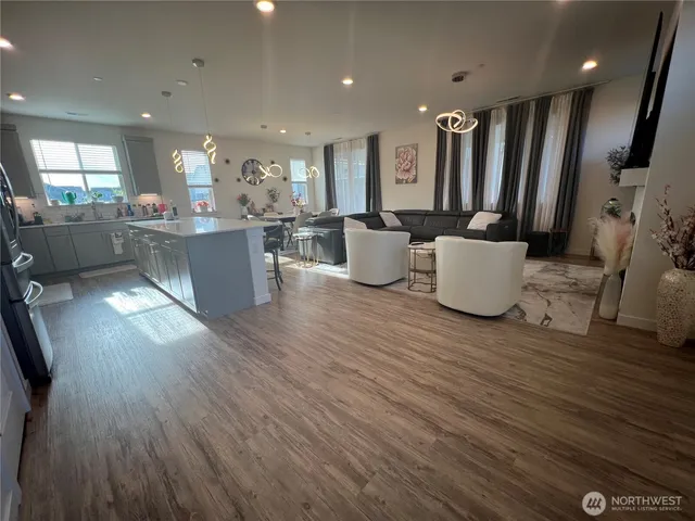 a living room with couches and kitchen view with wooden floor