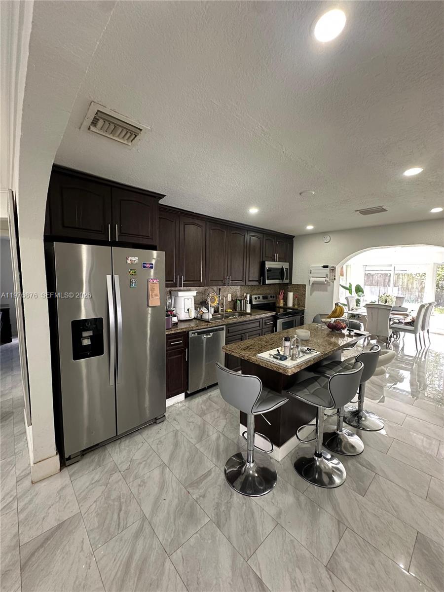 5710 Douglas Street Hollywood, FL 33021 - Photo 3 of 21 a kitchen with stainless steel appliances kitchen island granite countertop a sink refrigerator and cabinets