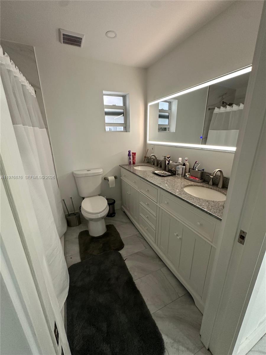 5710 Douglas Street Hollywood, FL 33021 - Photo 5 of 21 a bathroom with a double vanity sink and a mirror
