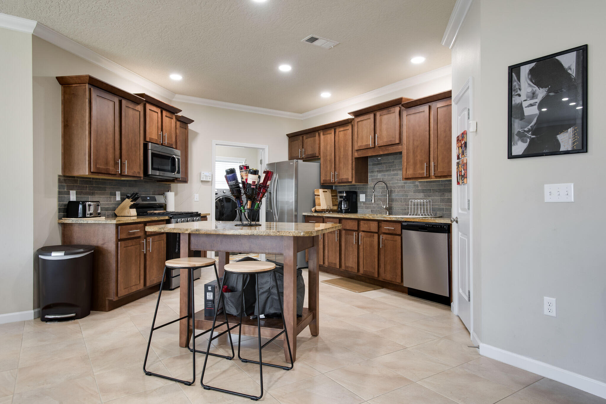 4600 Hermosa Road Crestview, FL 32539 - Photo 12 of 28 a kitchen with stainless steel appliances granite countertop a stove top oven a sink dishwasher a dining table and chairs with wooden cabinets
