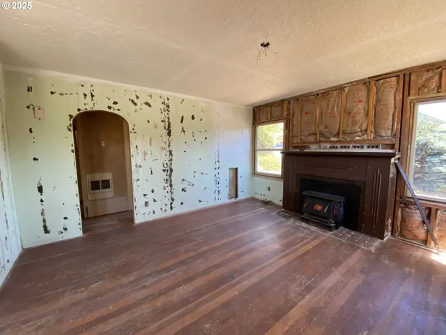 a view of an empty room with wooden floor and a fireplace