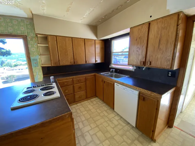 a kitchen with a sink a stove cabinets and a window