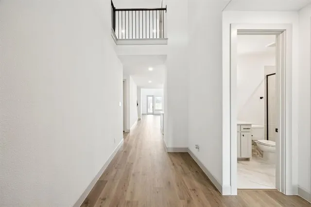 a kitchen with stainless steel appliances granite countertop a sink a stove a refrigerator and white cabinets with wooden floor