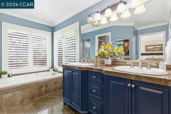 a bathroom with a granite countertop sink a large mirror a bathtub and next to a window