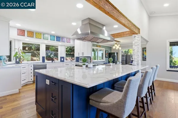 a room with stainless steel appliances kitchen island granite countertop a table chairs and a large window