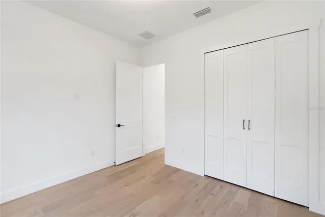 an empty room with a chandelier fan and windows
