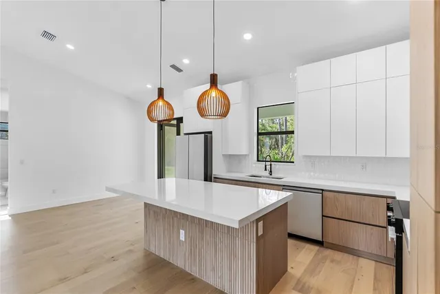 a large kitchen with a large window a refrigerator a oven and a sink