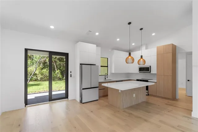 a kitchen with stainless steel appliances granite countertop a sink a microwave a refrigerator and a stove