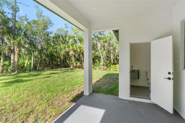 a white house with a big yard and large trees