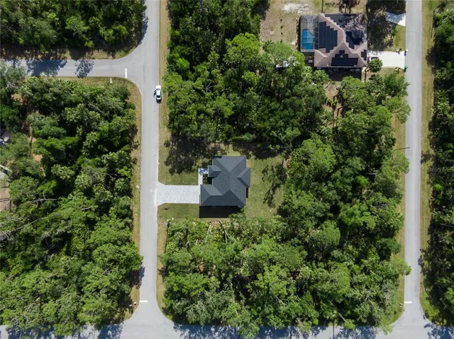 an aerial view of residential house with outdoor space and trees all around