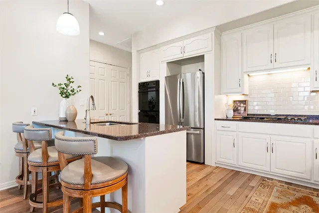 a kitchen with stainless steel appliances a dining table chairs and refrigerator