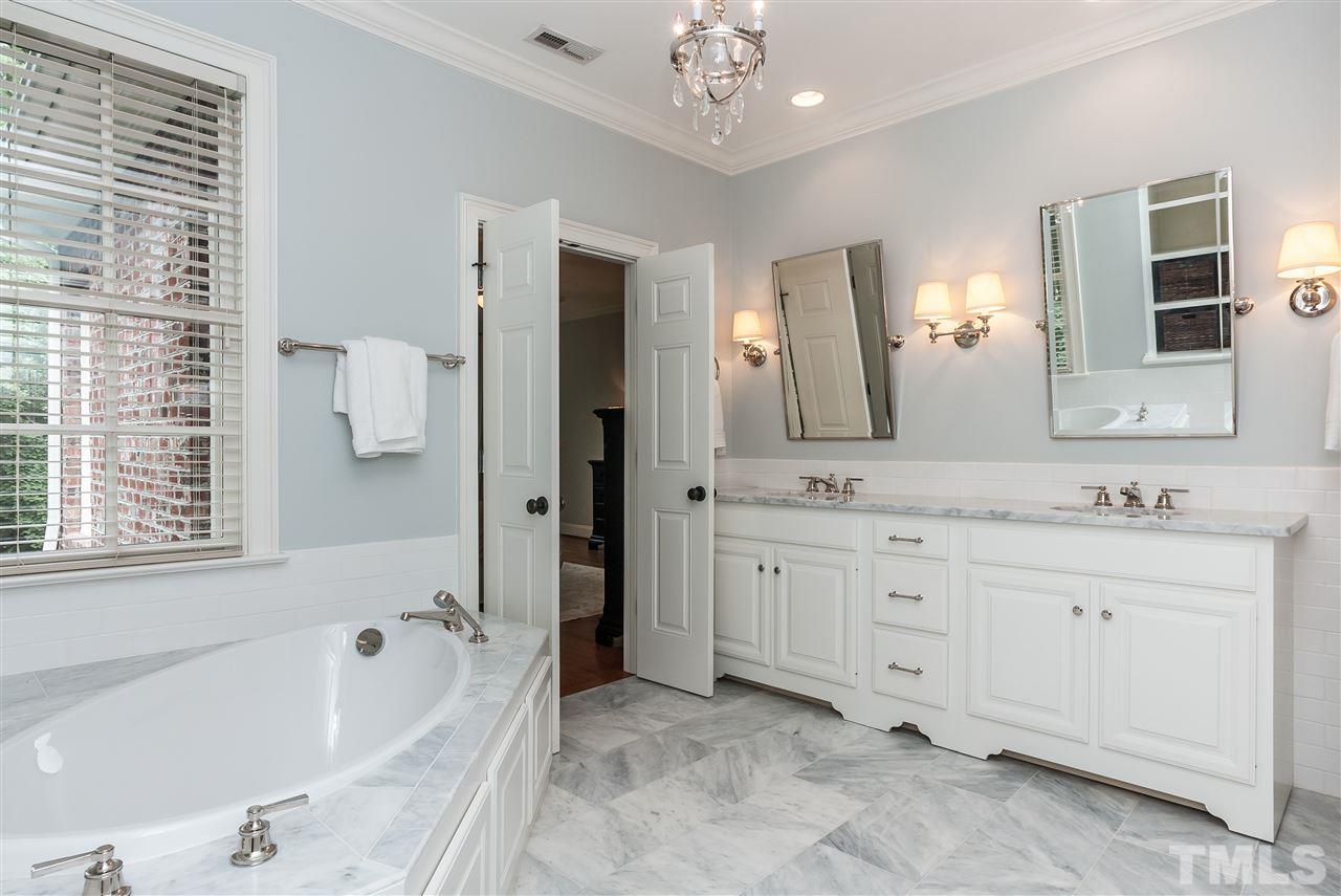 607 Runnymede Road Raleigh, NC 27607 - Photo 14 of 25 a spacious bathroom with a granite countertop sink a mirror a bathtub and shower
