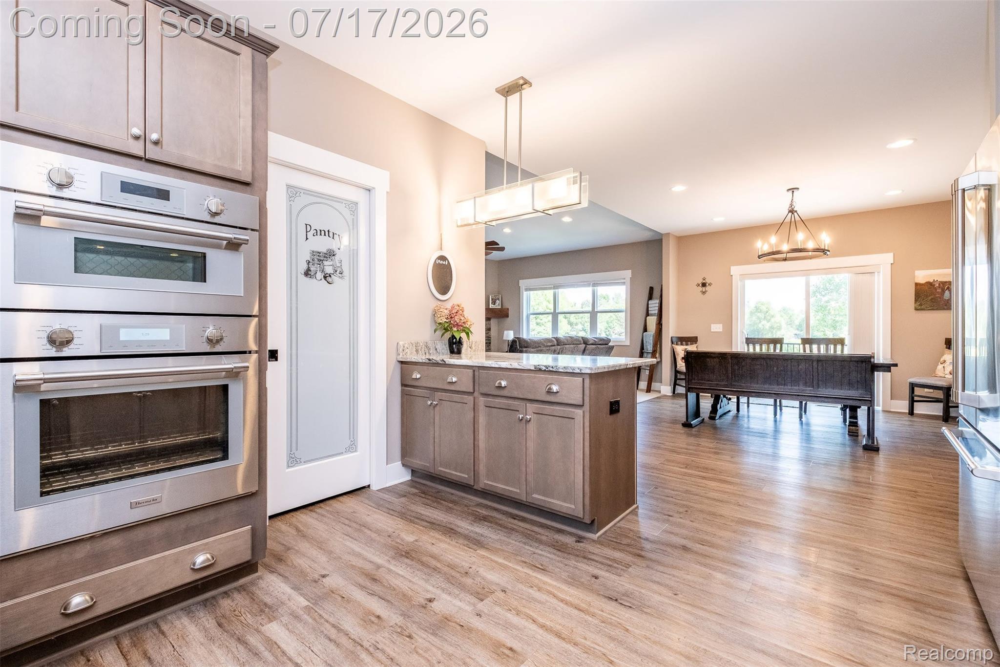 12349 Sugar Maple Drive Fenton, MI 48430 - Photo 19 of 67 Gourmet kitchen featuring stainless steel double ovens, a built-in microwave, and a pantry with a frosted glass door