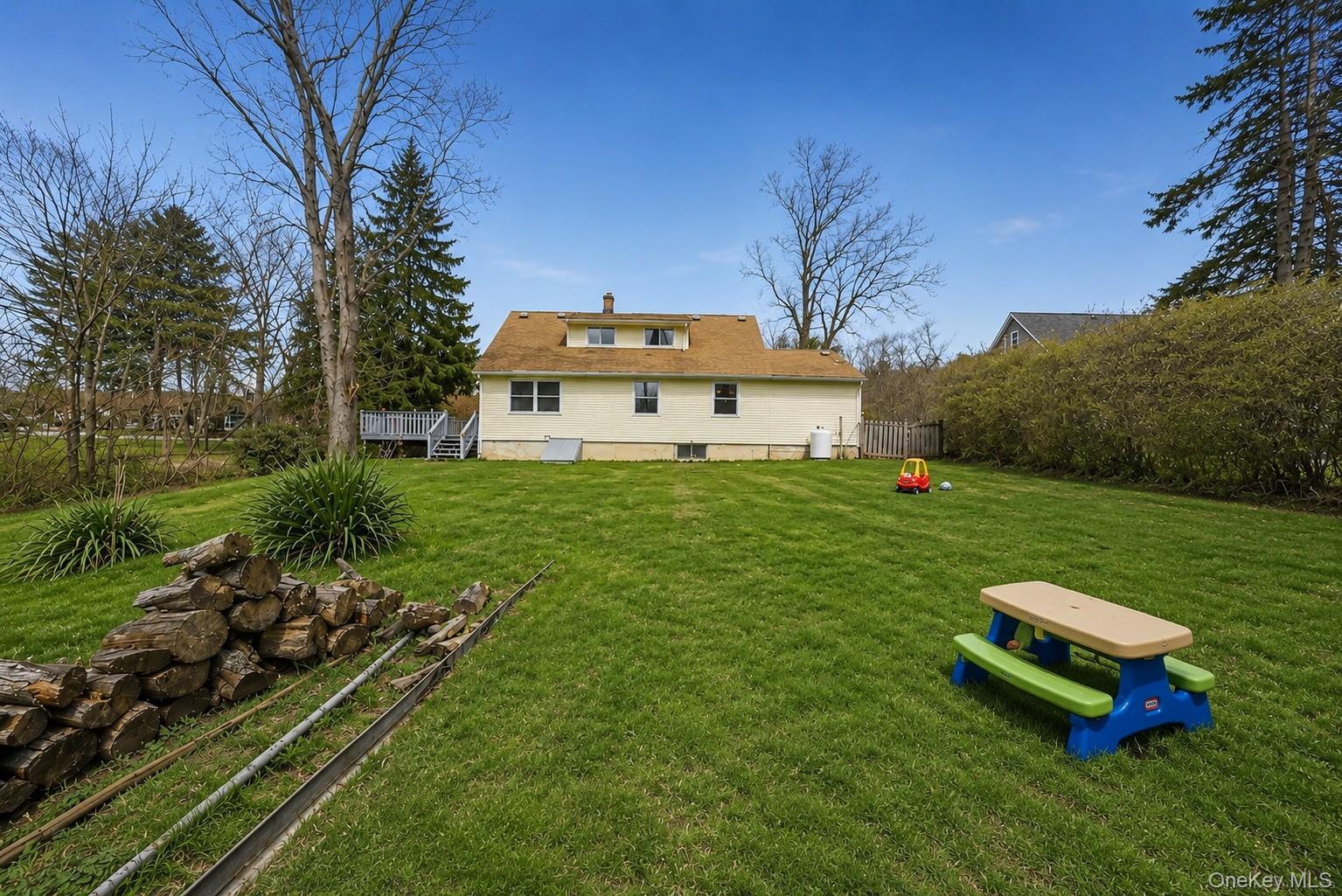 785 Locksley Road Yorktown Heights, NY 10598 - Photo 15 of 16 Expansive green lawn with mature trees and a rear house exterior featuring a deck with stairs photos have been digitally enhanced to illustrate the property's potential.