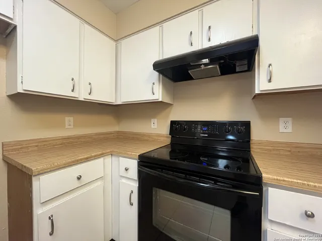 a kitchen with stainless steel appliances granite countertop white cabinets and a stove
