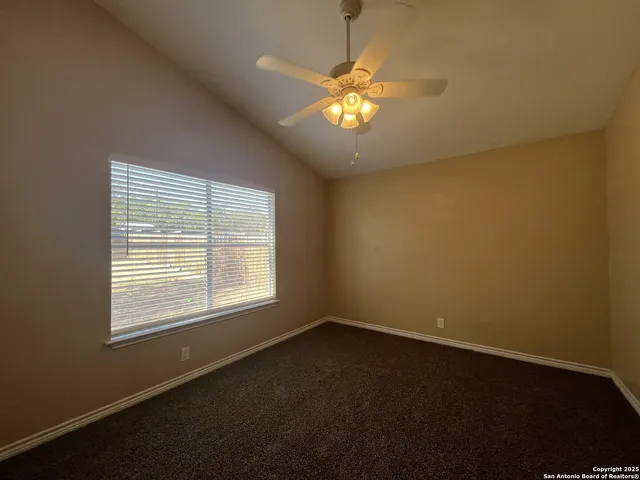 a view of an empty room with a chandelier fan and a window