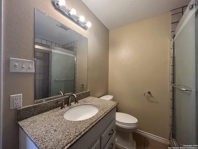 a bathroom with a granite countertop sink toilet and a mirror