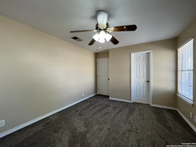 a view of an empty room and window and chandelier fan