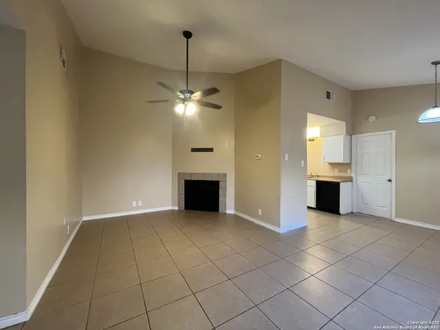 an empty room with kitchen view and fireplace