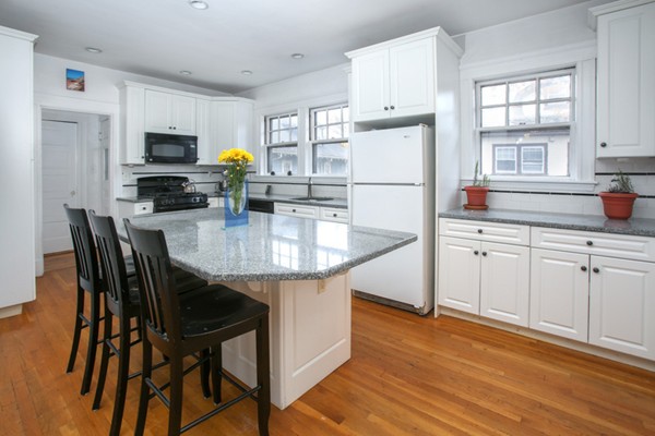 70 Abbottsford Road, Unit 2 Brookline, MA 02446 - Photo 2 of 13 a kitchen with stainless steel appliances granite countertop a dining table chairs refrigerator and microwave