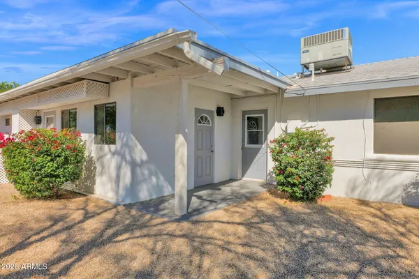 a view of a white house with a yard and potted plants