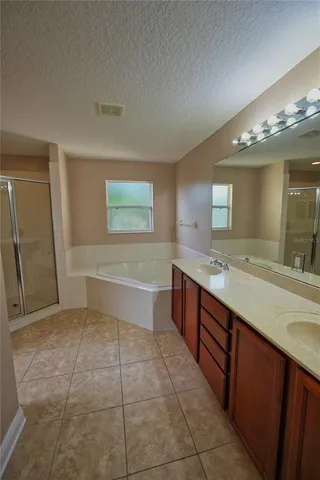 an empty room with wooden floor cabinet and windows