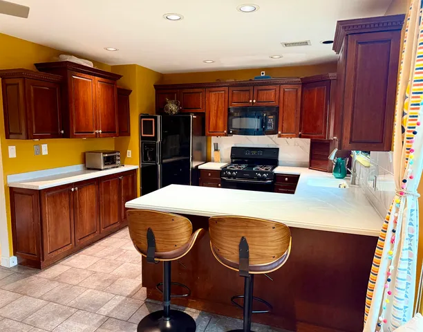 a kitchen with stainless steel appliances a stove a refrigerator a sink a dining table and chairs