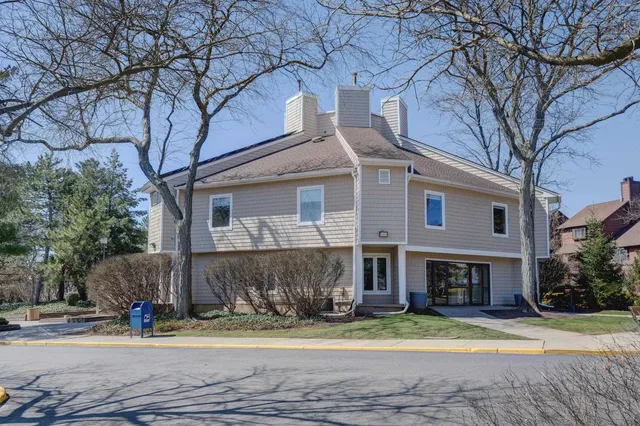a view of a brick house with a yard and large trees