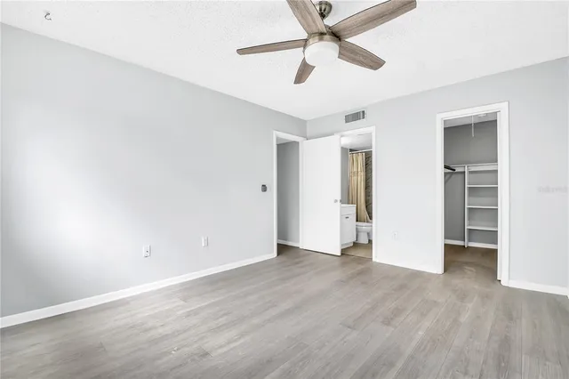 an empty room with wooden floor ceiling fan and windows