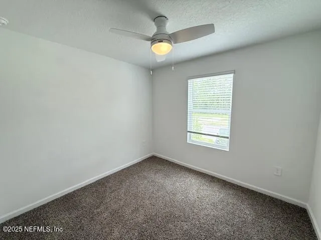 an empty room with a window and a ceiling fan