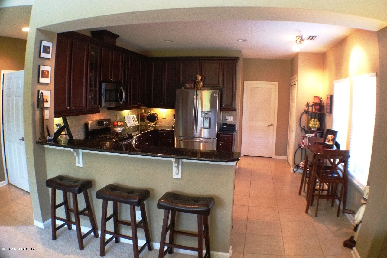 6092 White Tip Road Jacksonville, FL 32258 - Photo 10 of 32 a kitchen with stainless steel appliances kitchen island granite countertop a table and chairs in it