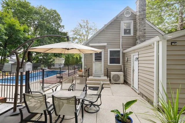 a view of patio with chairs and table under an umbrella with a barbeque