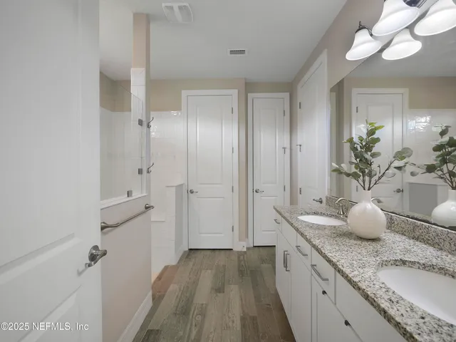 a en suite bathroom with a granite countertop sink a mirror and a shower