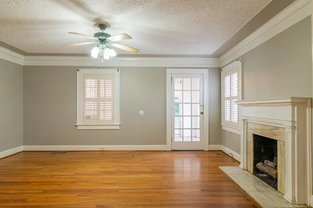 a view of an empty room with chandelier fan and fire place