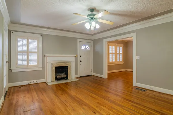 a view of an empty room with wooden floor and a window