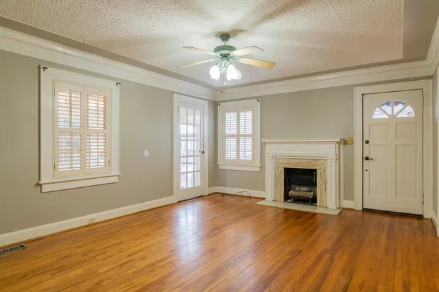 an empty room with wooden floor fan and windows
