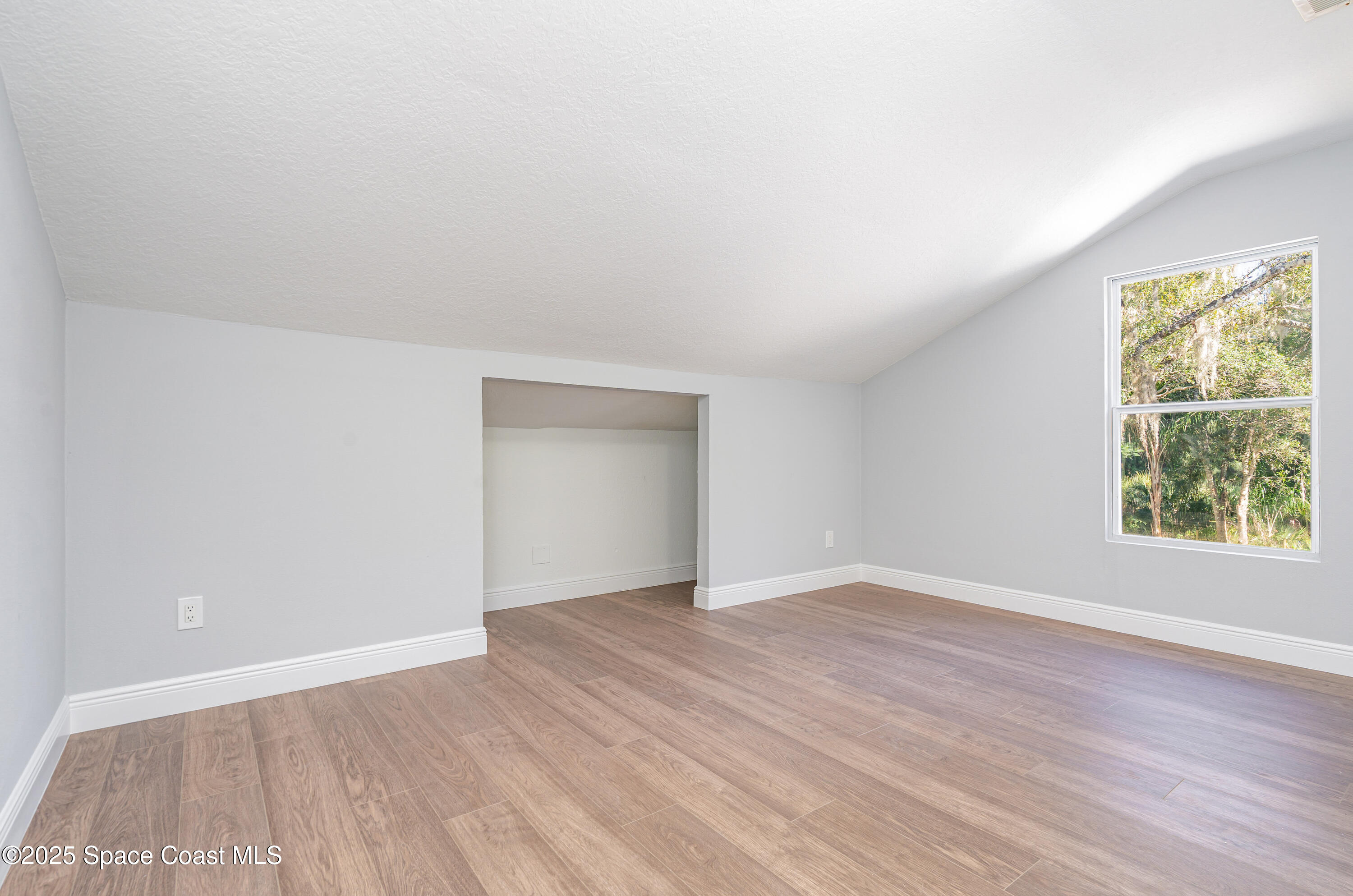 1735 Marywood Road Melbourne, FL 32934 - Photo 12 of 25 an empty room with wooden floor and windows