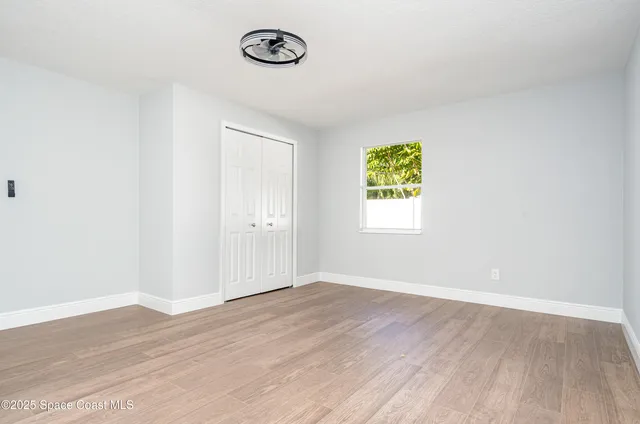 an empty room with a window and a ceiling fan