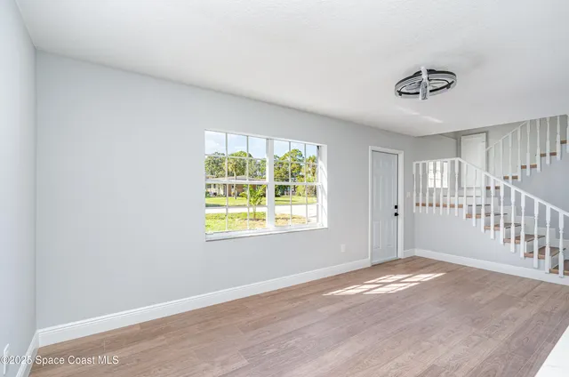 a view of an empty room with wooden floor and a window