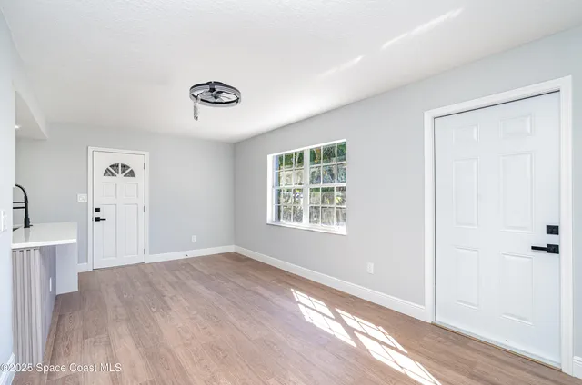 a view of an empty room with wooden floor and a window